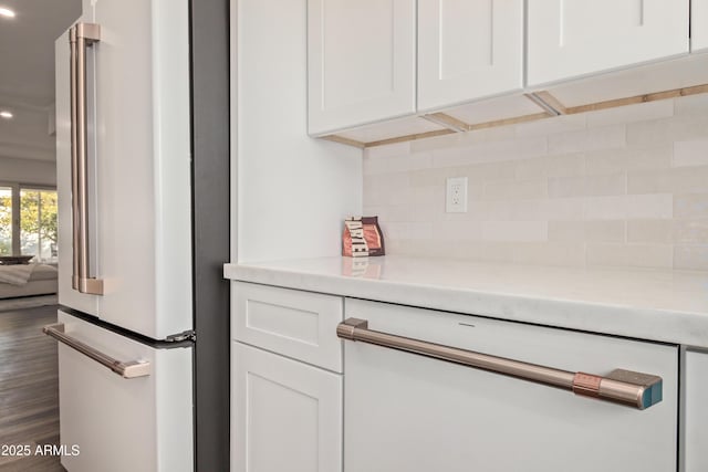 interior details featuring white cabinetry, high end fridge, and tasteful backsplash