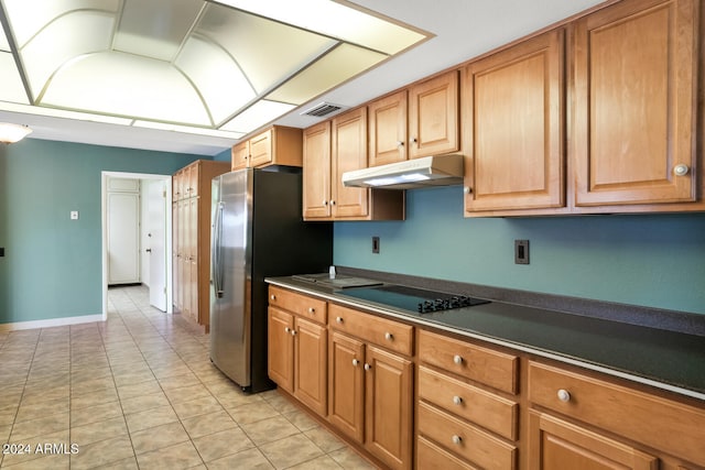 kitchen featuring black electric stovetop, stainless steel refrigerator, and light tile patterned flooring