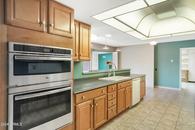 kitchen featuring dishwasher, double oven, sink, and light tile patterned floors