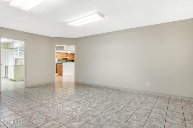 tiled spare room with a textured ceiling and sink