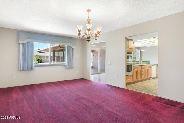 empty room with sink, a textured ceiling, light colored carpet, and an inviting chandelier