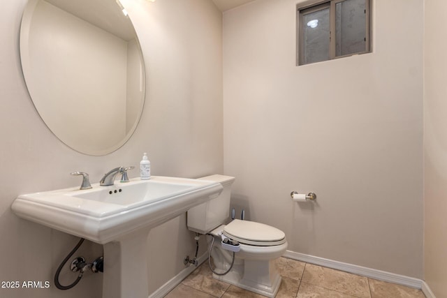 bathroom featuring baseboards, toilet, and a sink