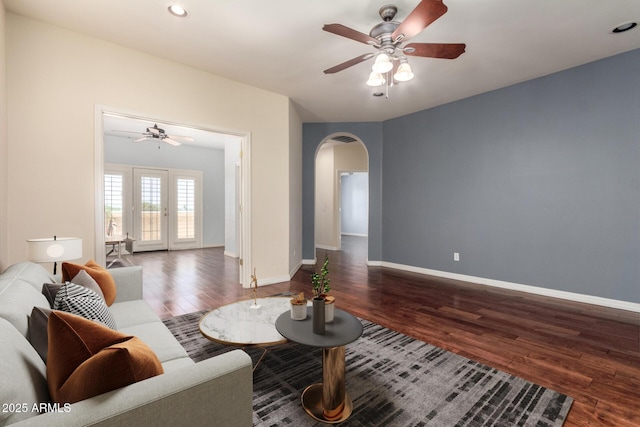 living room with baseboards, wood finished floors, ceiling fan, and arched walkways