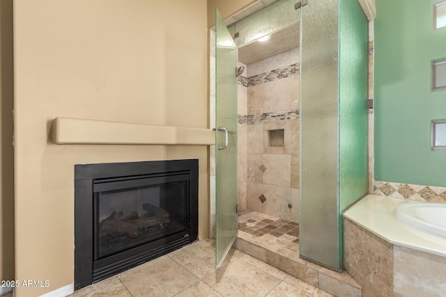 bathroom featuring tile patterned floors, a stall shower, a bath, and a glass covered fireplace