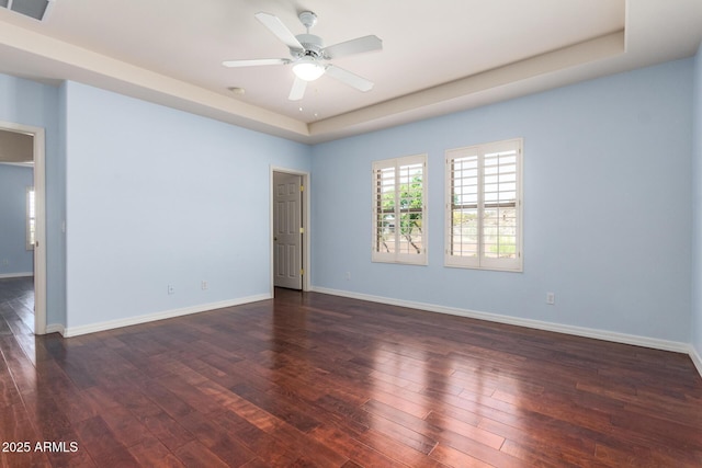 unfurnished room featuring dark wood-style floors, ceiling fan, a raised ceiling, visible vents, and baseboards