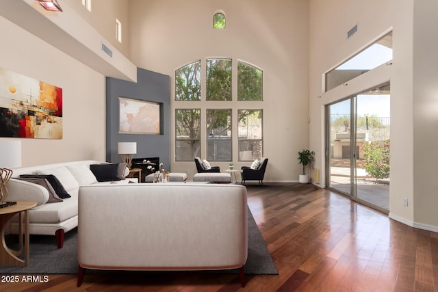 living room with dark wood-style floors, visible vents, and a high ceiling