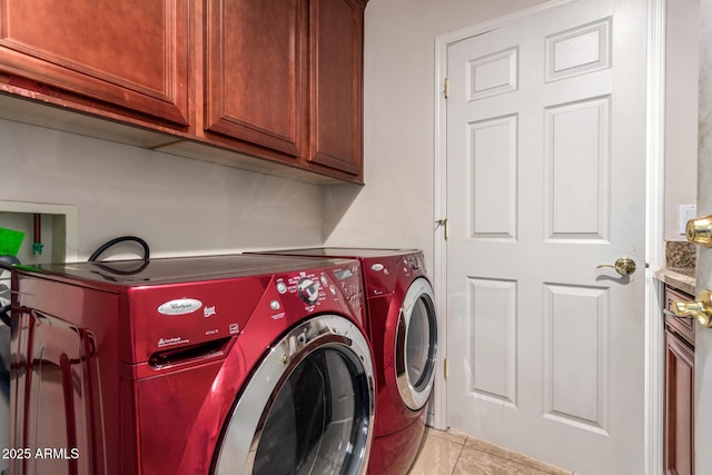 laundry area featuring light tile patterned floors, separate washer and dryer, and cabinet space