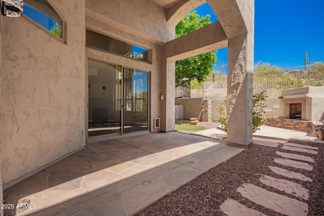 view of patio featuring fence and an outdoor fireplace