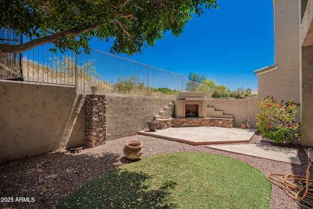 view of yard with a patio, an outdoor fireplace, and a fenced backyard