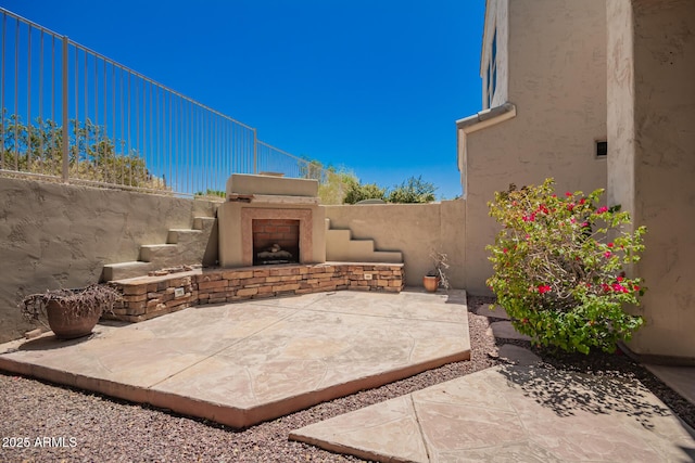 view of patio with fence and an outdoor fireplace