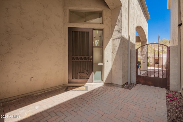 doorway to property featuring stucco siding and a gate