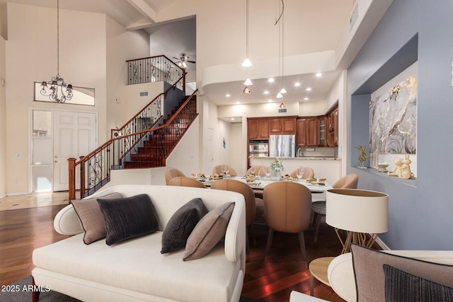 living room with stairway, wood finished floors, ceiling fan, and a high ceiling