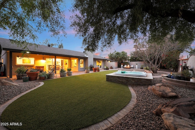 back of property at dusk featuring a yard, a patio area, and a fenced backyard