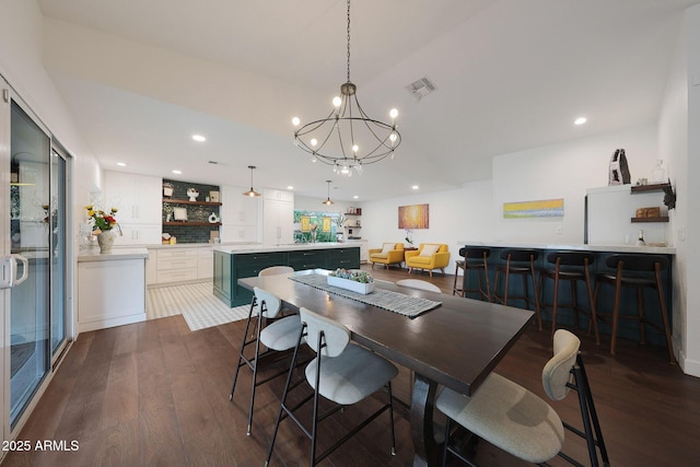 dining area featuring visible vents, dark wood finished floors, bar, an inviting chandelier, and recessed lighting