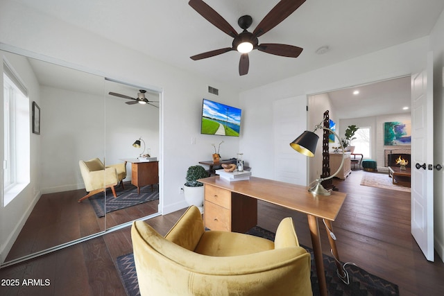 office featuring wood-type flooring, a fireplace, visible vents, and baseboards