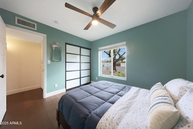 bedroom with a closet, visible vents, ceiling fan, wood finished floors, and baseboards