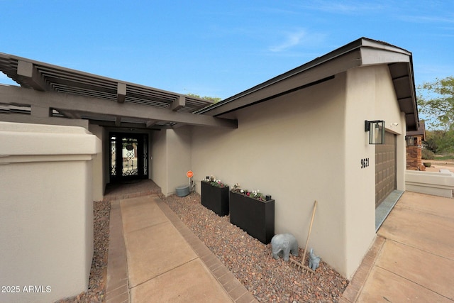 entrance to property with a garage and stucco siding