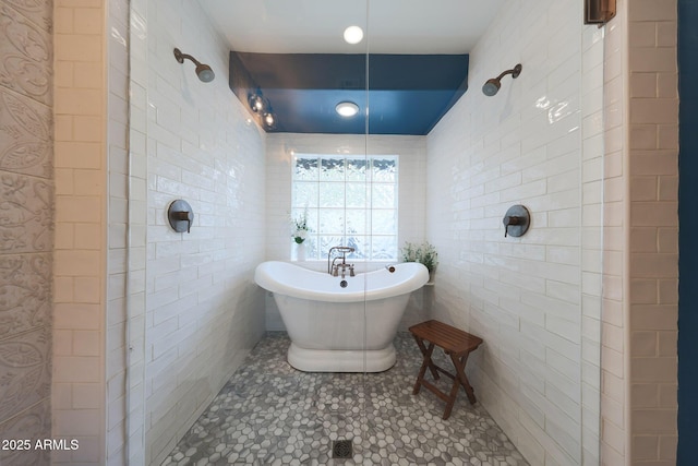 bathroom featuring a freestanding tub, a tile shower, and tile walls