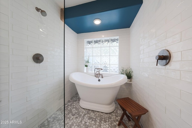 full bathroom featuring tile walls, walk in shower, a freestanding bath, and tile patterned floors