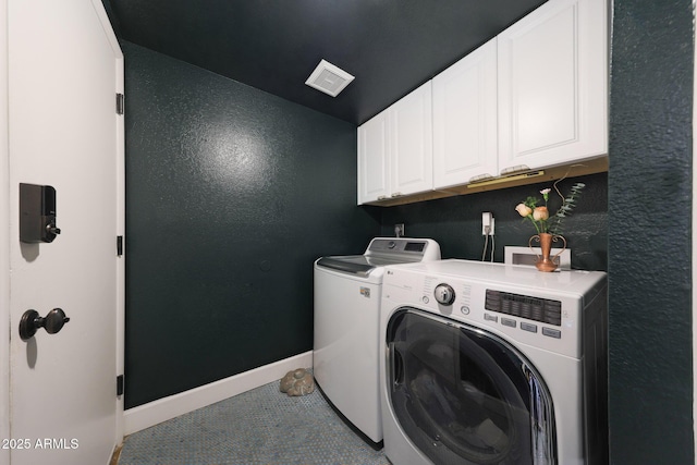 clothes washing area featuring a textured wall, visible vents, baseboards, washer and dryer, and cabinet space