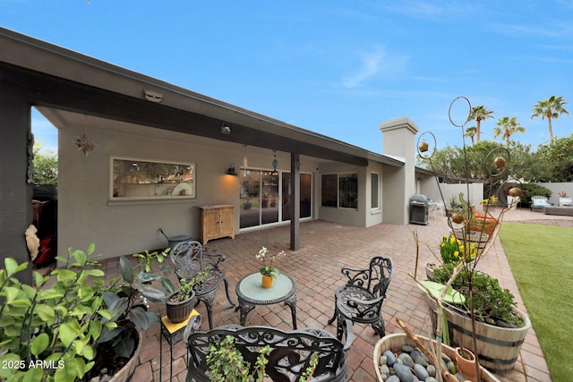 back of property with a chimney, a patio, fence, and stucco siding