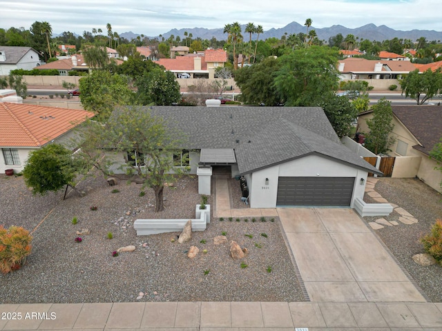 view of front of property featuring a garage, concrete driveway, roof with shingles, a mountain view, and stucco siding