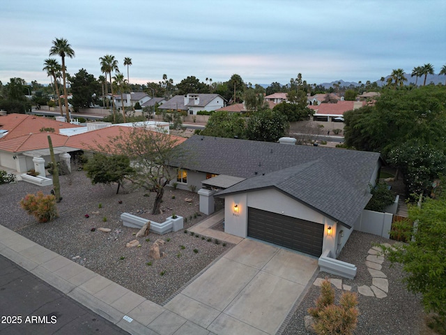 view of front of house with a garage, a shingled roof, concrete driveway, fence, and stucco siding