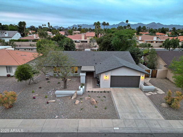 view of front of property with a mountain view, a garage, fence, driveway, and stucco siding