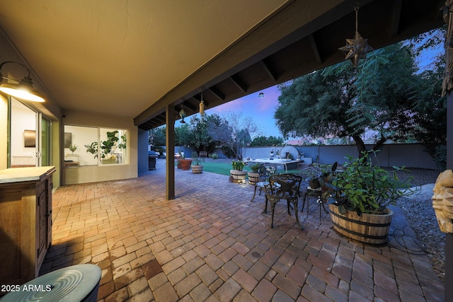 patio terrace at dusk with a fenced backyard and outdoor dining space