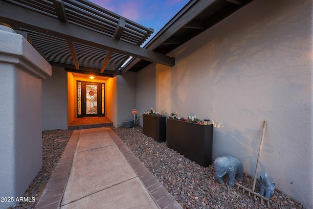 doorway to property with a pergola and stucco siding