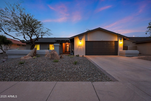 mid-century modern home featuring a garage, concrete driveway, and stucco siding