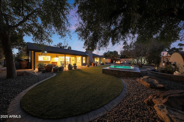 back of house at dusk with a patio, a yard, fence, and an outdoor pool