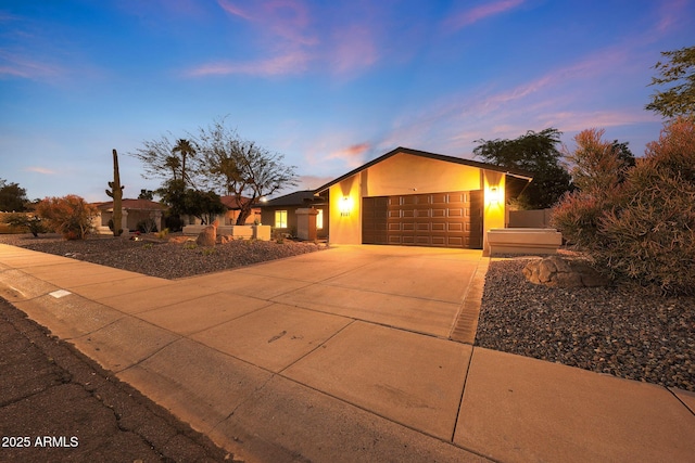 mid-century inspired home featuring a garage, driveway, and stucco siding