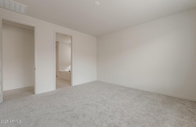 unfurnished bedroom featuring ensuite bath and light colored carpet