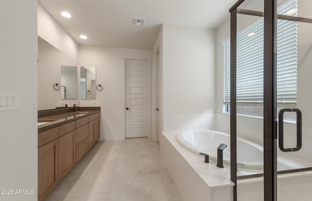 bathroom featuring tiled tub, vanity, and tile patterned floors