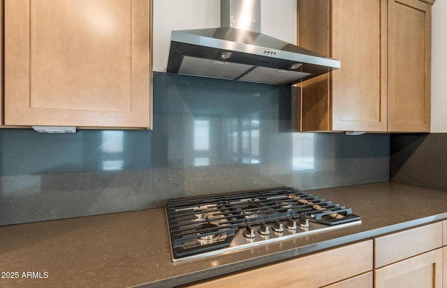 kitchen featuring wall chimney exhaust hood, stainless steel gas stovetop, decorative backsplash, and light brown cabinets