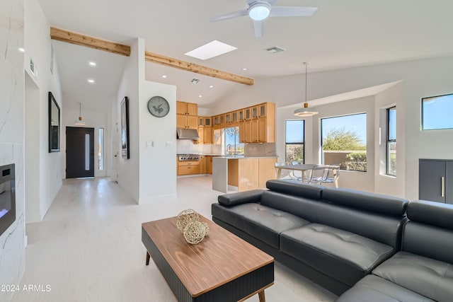 living room with sink, ceiling fan, and vaulted ceiling with skylight