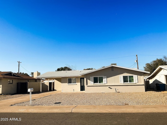 ranch-style home with a carport, fence, and brick siding