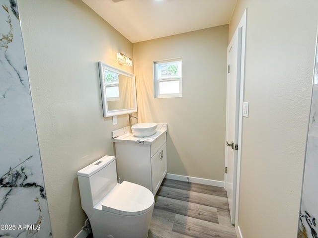 bathroom featuring baseboards, toilet, wood finished floors, and vanity