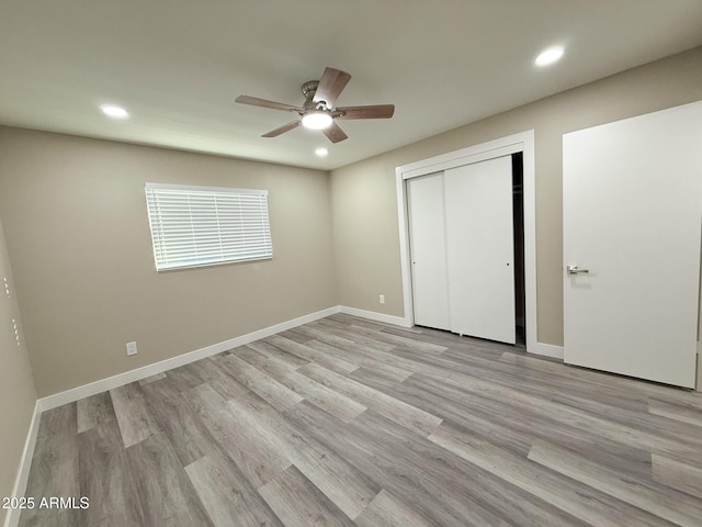 unfurnished bedroom with recessed lighting, a closet, baseboards, and wood finished floors