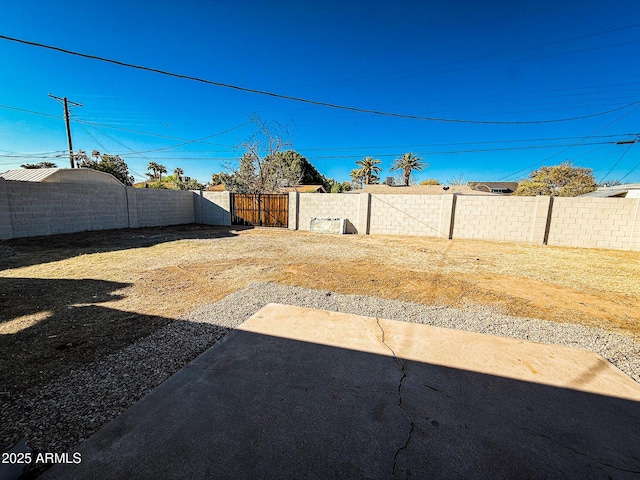view of yard with a patio, a fenced backyard, and a gate