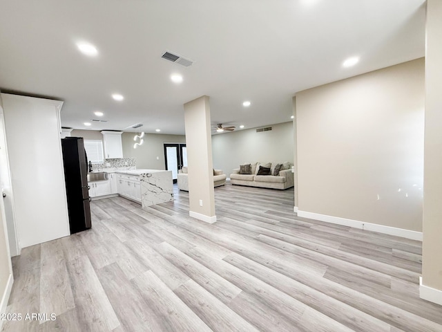 kitchen with visible vents, open floor plan, light countertops, freestanding refrigerator, and a ceiling fan
