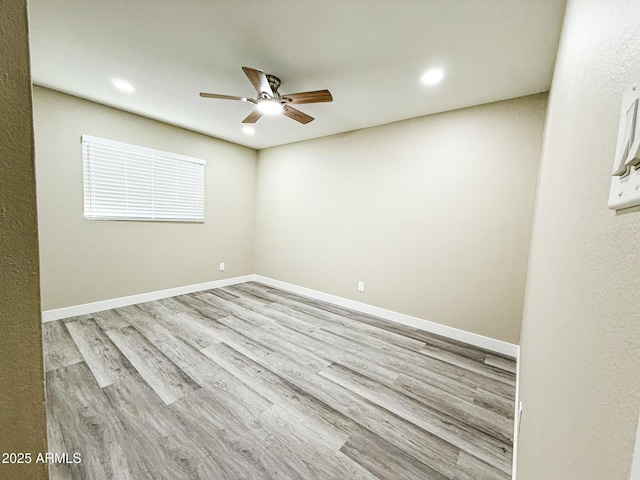 empty room with wood finished floors, a ceiling fan, and baseboards
