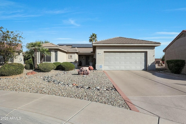 single story home with a garage and solar panels