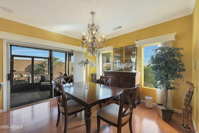 dining area with hardwood / wood-style floors, ornamental molding, and a chandelier