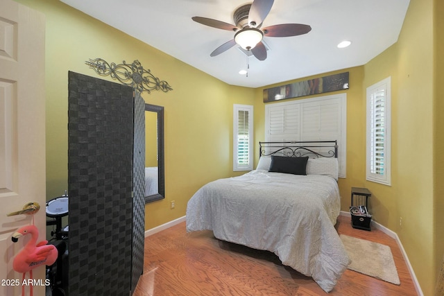 bedroom featuring ceiling fan, multiple windows, and hardwood / wood-style floors