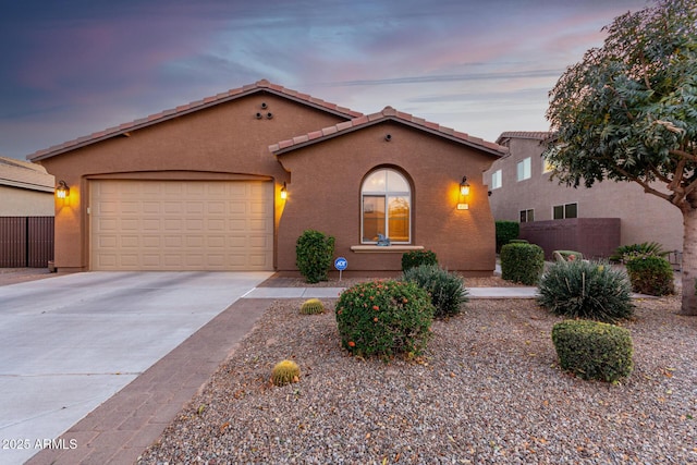 mediterranean / spanish-style house featuring driveway, a garage, fence, and stucco siding