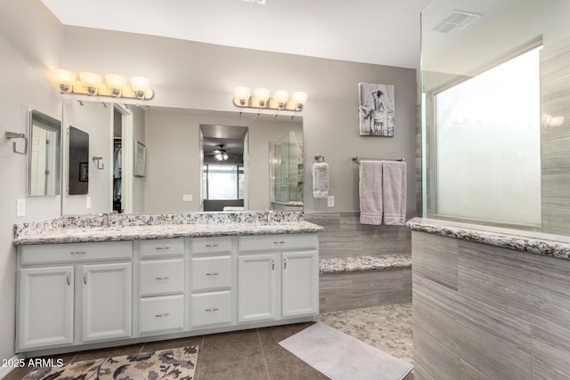 full bath featuring ceiling fan, tile patterned flooring, visible vents, tiled shower, and double vanity