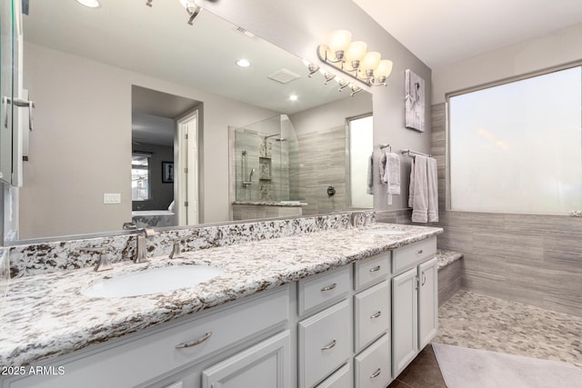 bathroom featuring double vanity, tiled shower, tile patterned flooring, and a sink