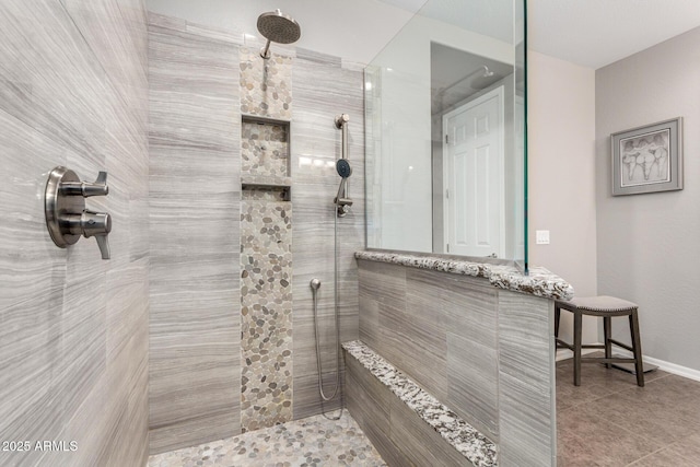 full bathroom featuring a tile shower, baseboards, and tile patterned floors